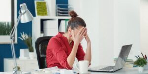 mulher na frente do computador com as mãos na cabeça