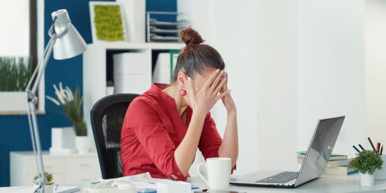 mulher na frente do computador com as mãos na cabeça